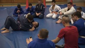 Students study as an instructor demonstrates an escape from a pinning technique.